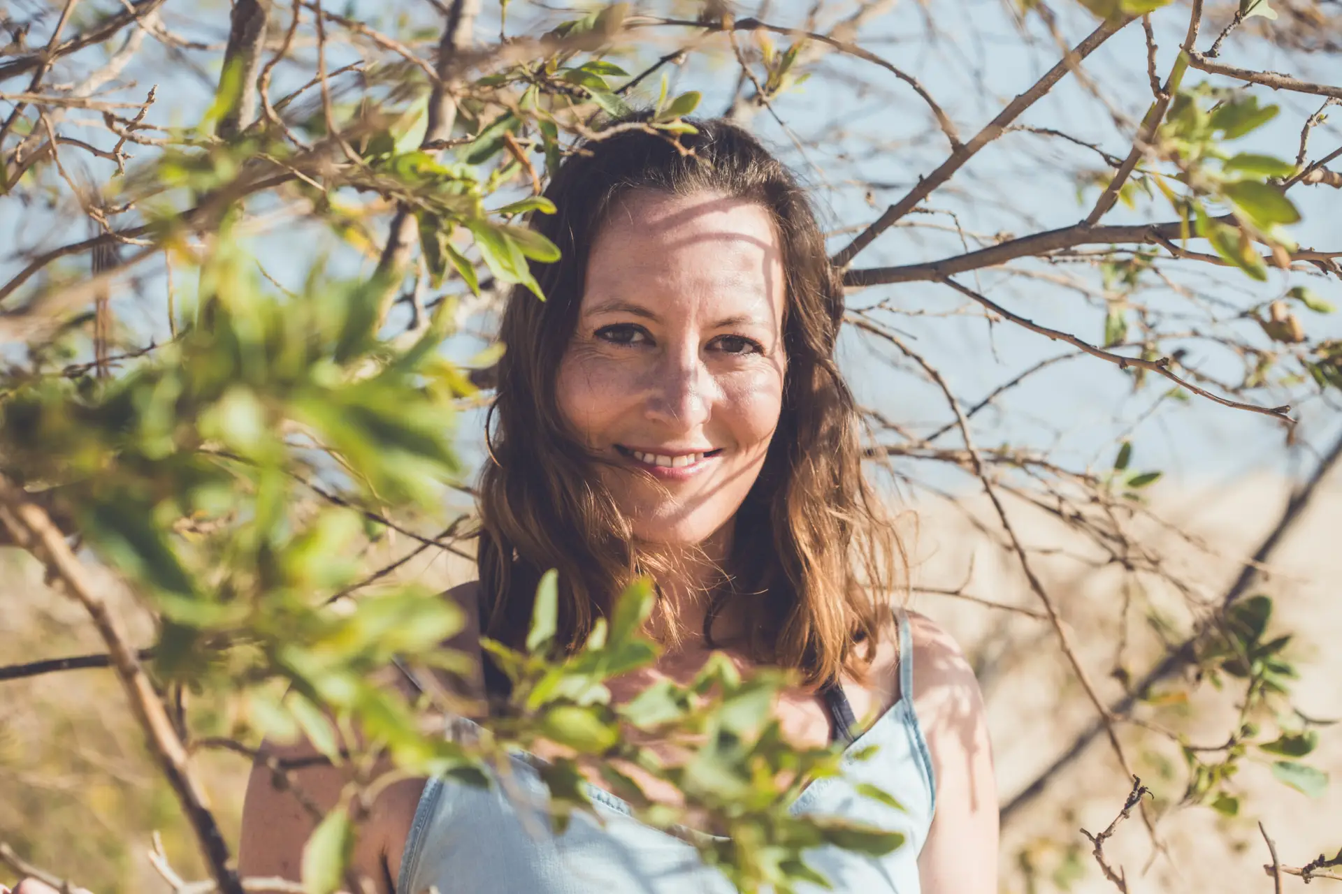 Sandra Dorschner lächelt zwischen grünen Zweigen in die Kamera.