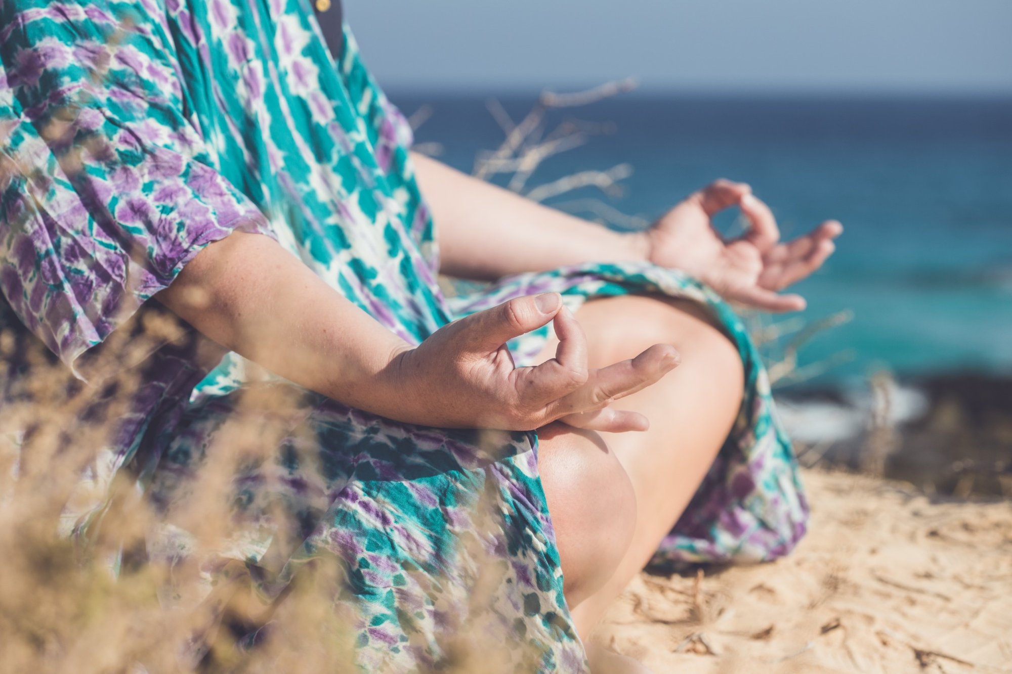 Meditation am Meer mit Blick auf Hände in Meditationshaltung
