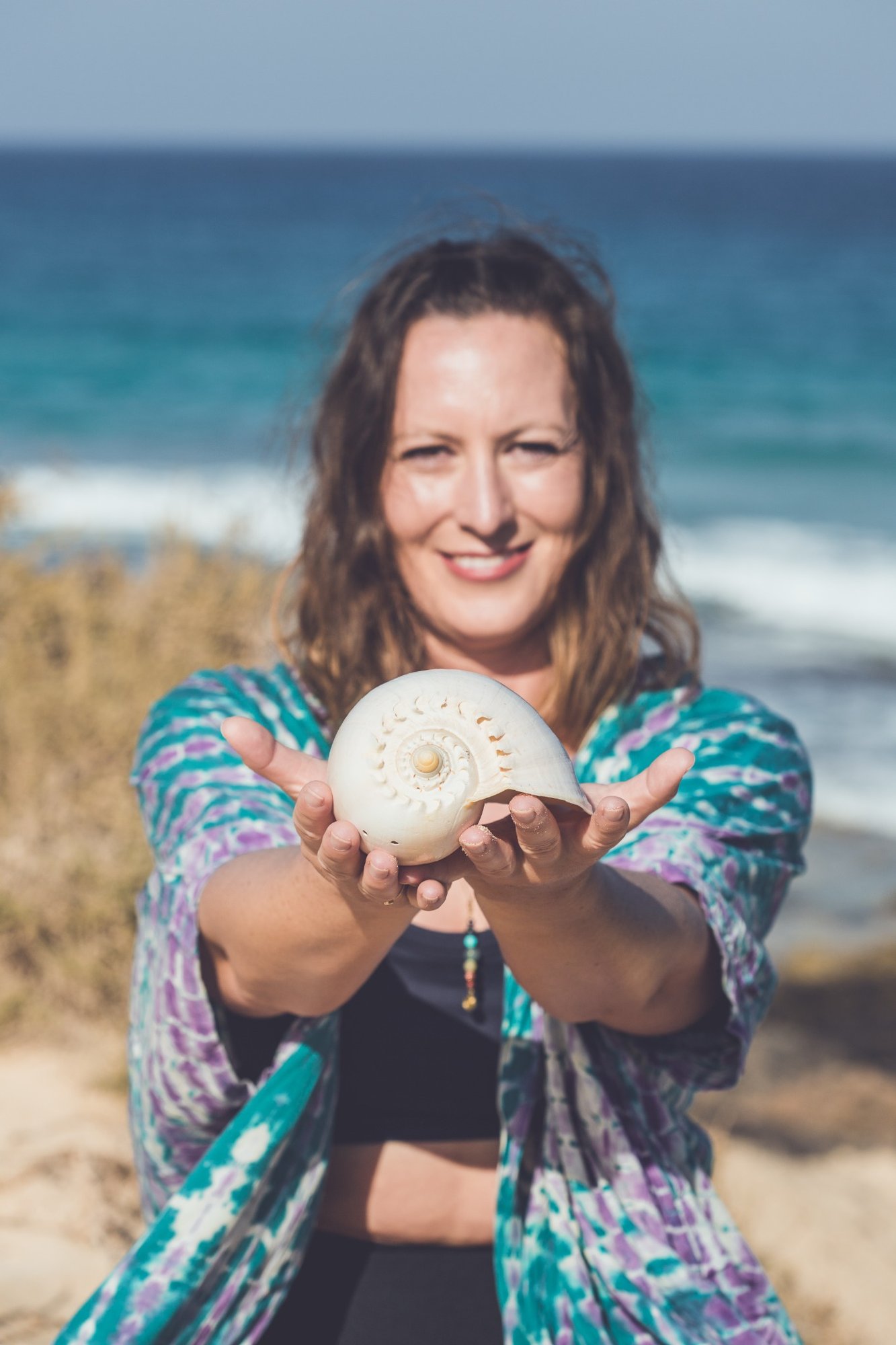 Sandra hält eine Muschel vor dem Meer in den Händen